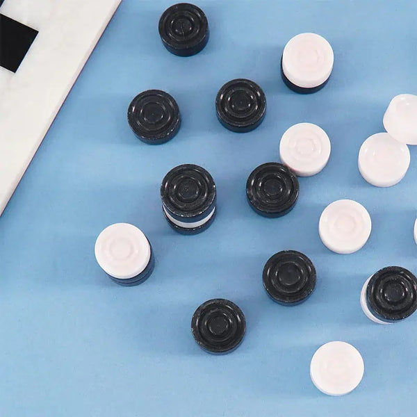 Black and white marble checkers discs scattered on blue surface — concentric ring and felt bottom detail by RADICALn