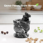 Black zebra marble mortar and pestle on a kitchen counter with whole peppercorns, cardamom pods and fresh coriander