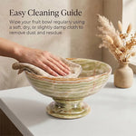 Green onyx marble pedestal fruit bowl being wiped clean with a cloth on a countertop