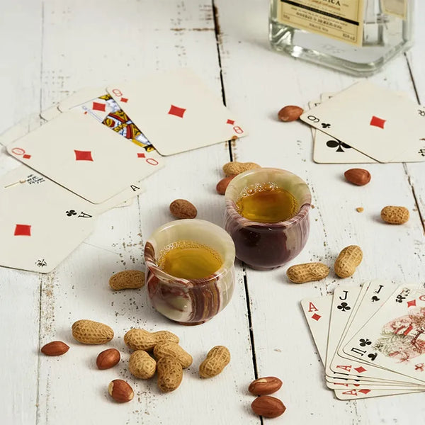 Pair of green onyx marble shot glasses filled for a poker night with cards and peanuts