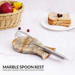 Green onyx marble spoon rest holding a whisk on a kitchen counter with fruit and toast