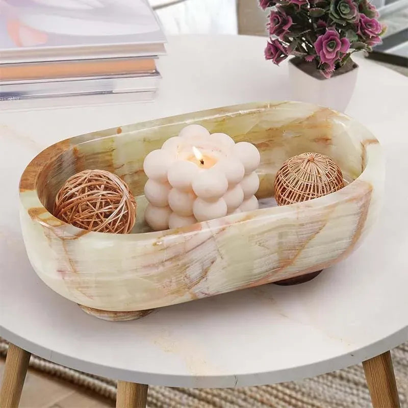 Green onyx footed marble trinket bowl holding a candle and rattan balls on a coffee table