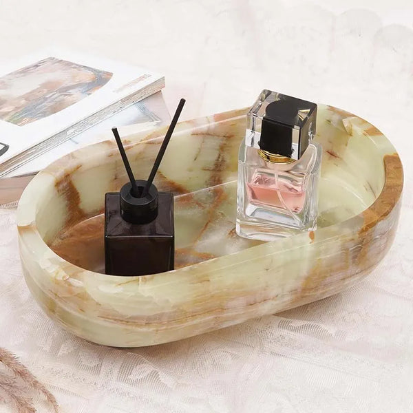 Green onyx oval marble trinket dish holding a reed diffuser and perfume beside books