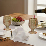 Red wine poured into a green onyx marble wine glass at a set dinner table