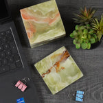 Green onyx square marble coasters on a dark desk beside a laptop and succulent