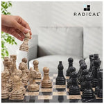 Hand lifting fossil coral marble rook piece — black and fossil coral marble chess set 15 inch standard set in home living room by RADICALn