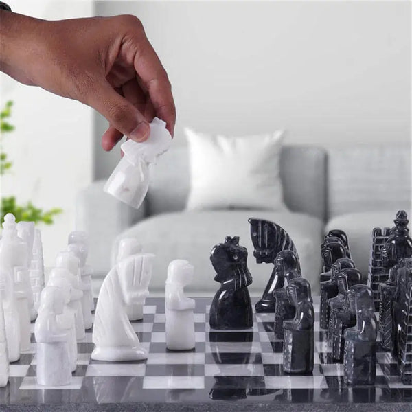 Hand lifting white antique marble pawn — black and white antique marble chess set 15 inch medieval figurative pieces in home setting by RADICALn