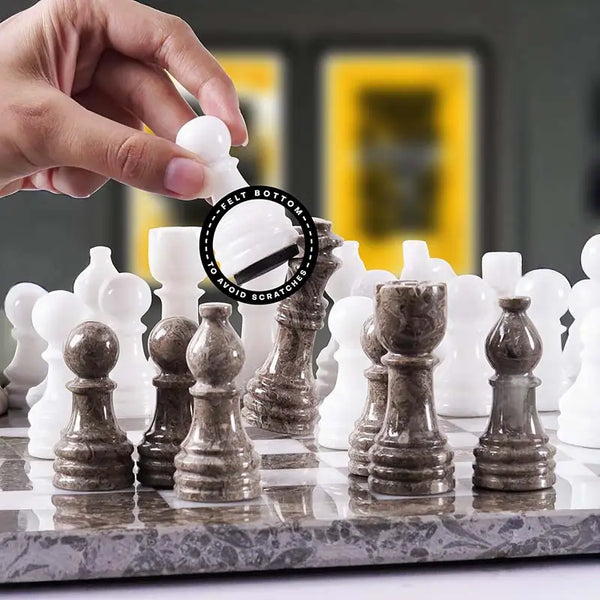 Hand lifting white chess pawn with felt bottom detail — white and grey oceanic pieces in starting position by RADICALn