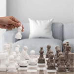 Hand lifting white marble pawn piece — oceanic grey and white marble chess set 15 inch in contemporary home living room by RADICALn