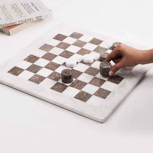 Hand placing oceanic marble checkers disc mid-game — white and oceanic marble checkers set 15 inch with books by RADICALn