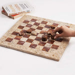 Hand placing red marble checkers disc mid-game — coral and red marble checkers set 15 inch with books and candle by RADICALn