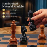 Handcrafted Black & Golden Marble Chess Set pieces, with a hand lifting the polished black marble king
