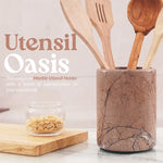 Marinara marble crock for utensils holding wooden spatulas on a kitchen countertop