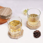 Natural brown octagon marble coasters under two whiskey glasses on a white table