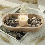Natural brown oval marble tray holding a candle and river pebbles on a styled coffee table