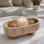 Natural brown footed marble trinket bowl holding a candle and rattan balls on a coffee table