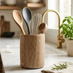 Natural brown marble utensil holder on a kitchen counter with wooden spoons, whisk and scoop
