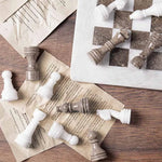 Oceanic grey and white marble chess pieces scattered on book pages — board corner detail by RADICALn