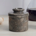 Handmade oceanic marble butter keeper with domed lid on a kitchen counter beside eggs