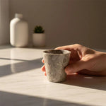 Hand holding a oceanic marble shot glass on a marble table
