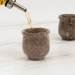 Drink being poured into a oceanic marble shot glass on a marble surface