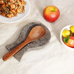 Oceanic marble utensil rest holding a wooden spoon beside a plate of noodles