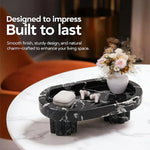 Raised black marble tray on fluted legs holding earbuds and a vase on a side table