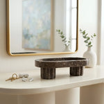 Raised oceanic marble tray on an entryway console beside keys and earbuds under a mirror