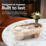 Raised travertine marble tray on fluted legs holding earbuds and a vase on a side table