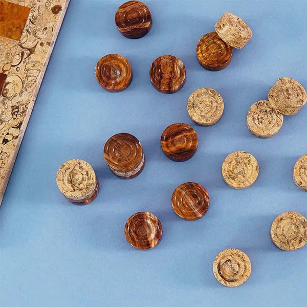 Red and fossil coral marble checkers discs scattered on blue surface — concentric ring and felt bottom detail by RADICALn