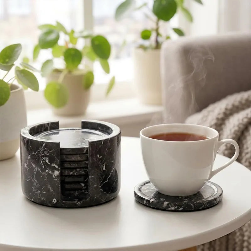 Round black marble coaster set and holder on a coffee table with a cup of tea