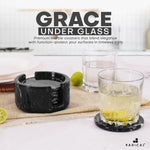Round black marble coaster set and holder beside drinking glasses on a kitchen counter