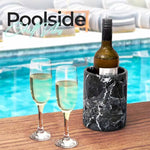 Round black marble wine cooler chilling a bottle beside two champagne flutes poolside