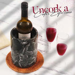 Round black marble wine cooler on a rattan coaster with two glasses of red wine