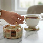 Hand lifting a tea cup from a round green onyx marble coaster beside its matching stone holder