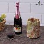 Round green onyx marble wine chiller and a wine bottle on a dining table with a glass
