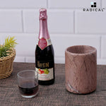Round marinara marble wine chiller and a wine bottle on a dining table with a glass