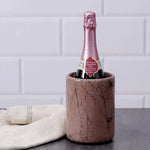Round marinara marble wine cooler chilling a sparkling bottle beside a linen towel on dark wood