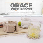 Round natural brown marble coaster set and holder beside drinking glasses on a kitchen counter