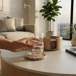 Round natural marble coaster set with holder on a living room coffee table under a glass of water