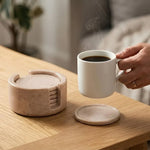 Hand lifting a tea cup from a round verona marble coaster beside its matching stone holder