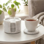 Round white marble coaster set and holder on a coffee table with a cup of tea