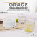 Round white marble coaster set and holder beside drinking glasses on a kitchen counter