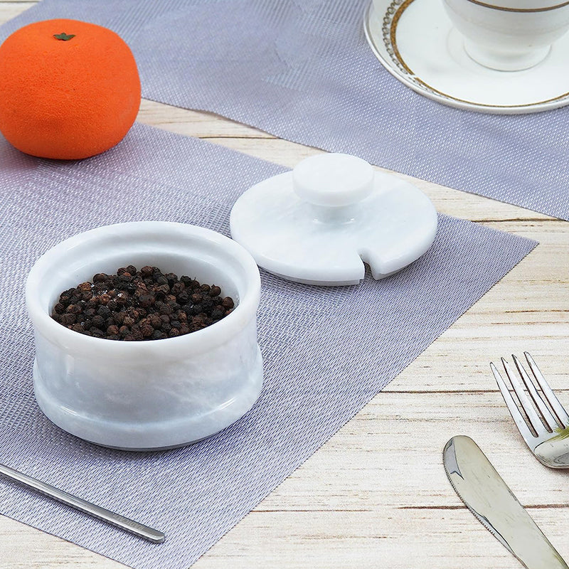 White marble salt cellar with stainless steel spoon, adding elegance to your kitchen counter.