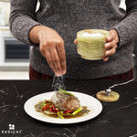 Salt being sprinkled onto a plated steak from a green onyx marble seasoning keeper held in hand