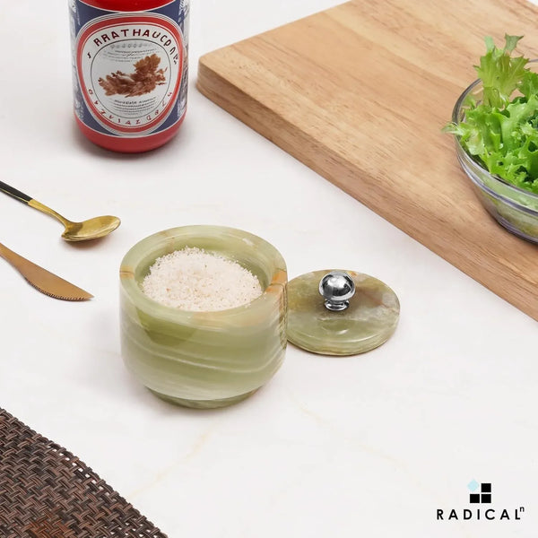 Small green onyx marble seasoning keeper filled with salt, stainless steel knob lid set to the side on a countertop