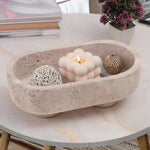 Travertine footed marble trinket bowl holding a candle and rattan balls on a coffee table