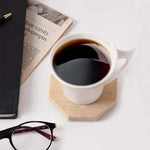 Verona octagon marble coaster under a white coffee cup beside a newspaper and glasses