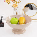 Verona marble pedestal fruit bowl holding a green apple and persimmon on a console table beside a vase and mirror