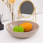 Verona marble fruit bowl holding a green apple and a mango on a console table beside a vase and mirror